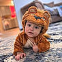 Michael joined the competition — help win amazing prizes! baby, child, costume, lion, plush, cute, indoor, carpet, rug, living_room, floor, crawling, face, expression, hood, animal_costume, soft, home, infant, curious