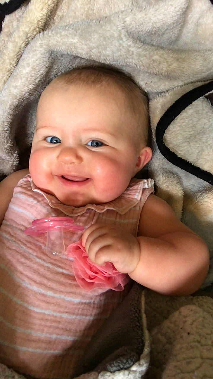 Mila is registered to the contest to win money with this photo: baby, baby_toddler_clothing, cheek, child, chin, eyebrow, eyelash, flash_photography, fun, gesture, happy, iris, lip, mouth, neck, nose, person, pink, skin, smile