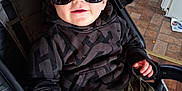 Cash is registered to the contest to win money with this photo: toddler, child, sunglasses, stroller, hoodie, curly_hair, smile, indoor, floor_tiles, camo_pants, hand, baby_clothing, seat, person, cute, casual, reflection, eyewear, cool, happy