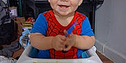 Cash is registered to the contest to win money with this photo: baby, blond_hair, child, cute, floor, food, furniture, happy, high_chair, indoor, messy, person, plastic, room, smiling, spiderman_shirt, table, toddler, tray, utensil