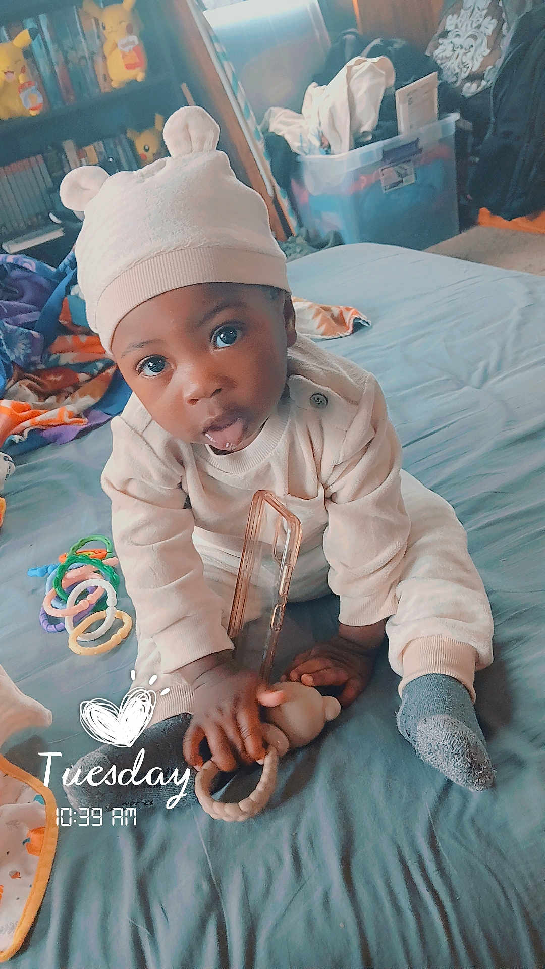 Kash'Mire joined the competition — help win amazing prizes! baby, infant, child, hat, onesie, sock, teether, toy_rings, phone_case, bed, blanket, blue_bedspread, bedroom, bookshelf, pikachu, storage_bin, wide_eyes, stuffed_toy, timestamp_overlay, text_overlay