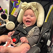 Everleigh is registered to the contest to win money with this photo: baby, car_seat, headband, bow, toy, teether, smiling, infant, child, happy, clothing, safety_harness, playful, cute, indoors, person, seat, closeup, comfort, accessory