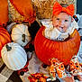 Everleigh is registered to the contest to win money with this photo: baby, pumpkin, orange_bow, fall_decor, blanket, autumn, child, smiling, cute, festive, white_pumpkin, orange_pumpkin, patterned_pants, barefoot, holiday, seasonal, indoors, hay_bale, decorative, portrait