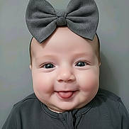Reella joined the competition — help win amazing prizes! baby, child, face, smile, tongue, bow, headwear, clothing, portrait, cute, infant, cheeks, eyes, gray, background, fashion, happy, young, closeup, person