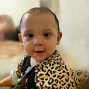 Abigail is registered to the contest to win money with this photo: toddler, child, face, eyes, smile, leopard_print, jacket, black_shirt, stars, indoor, blurred_background, person, cute, young_child, portrait, curly_hair, happy, baby, clothing, sitting