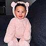 baby, child, pink, bear_suit, costume, smiling, cute, fluffy, indoors, couch, seated, portrait, happy, curly_hair, face, cozy, soft, playful, infant, person