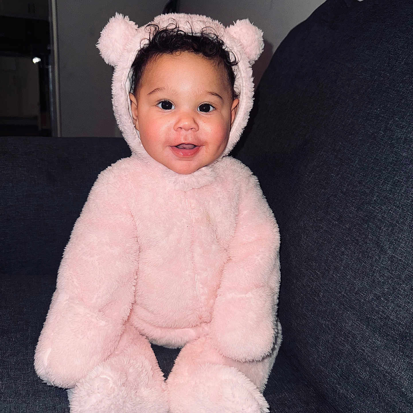 Kaleigha joined the competition — help win amazing prizes! baby, bear_suit, child, costume, couch, cozy, curly_hair, cute, face, fluffy, happy, indoors, infant, person, pink, playful, portrait, seated, smiling, soft