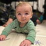 baby, child, crawling, green_striped_onesie, play_mat, indoor, face, hands, curious, smiling, blue_eyes, soft_lighting, background_blur, floor, person, infant, cute, home, young, portrait