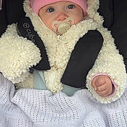 Maïa participe au concours pour gagner de l'argent avec cette photo : baby, infant, pacifier, pink_hat, pom_poms, fleece_jacket, cozy_blanket, car_seat, stroller, straps, blue_eyes, cheeks, hand, portrait, close_up, cute, warm_clothing, hat_label, blanket_knit, soft_texture
