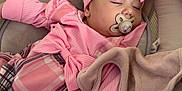 Maïa participe au concours pour gagner de l'argent avec cette photo : baby, infant, sleeping, pacifier, headband, bow, pink_clothing, plaid_pants, blanket, bassinet, bedding, plush_toy, hand, closed_eyes, newborn, cozy, soft_fabric, nursery, portrait, peaceful