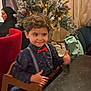 Adam participe au concours pour gagner de l'argent avec cette photo : child, boy, christmas_tree, holiday, indoor, high_chair, table, thumbs_up, red_bow_tie, suspenders, smile, curly_hair, ornaments, lights, woman, headscarf, curtain, furniture, festive, celebration
