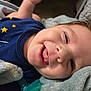 baby, smiling, tongue, blanket, blue_shirt, stars, face, closeup, happy, infant, soft_texture, child, cute, indoors, person, portrait, skin, head, expression, resting