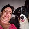 woman, person, dog, berner_mountain_dog, selfie, portrait, indoors, couch, fluffy, long_hair, black_white_brown, tongue, happy, smiling, face, pet, companion, pink_shirt, close_up, photography
