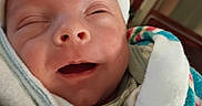 Ashland is registered to the contest to win money with this photo: newborn, baby, infant, face, portrait, sleepy, yawning, swaddled, blanket, hat, white_hat, textile, closeup, indoors, crib, nursery, soft_lighting, cute, peaceful, child