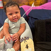 Fidel joined the competition — help win amazing prizes! baby, infant, smiling, baby_seat, onesie, socks, milestone_sign, wooden_sign, 4_months, face, hands, chubby_cheeks, indoor, cushions, cozy, cute, portrait, child, happy, dinosaur_print