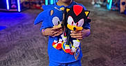 Euzaius joined the competition — help win amazing prizes! arcade, blue_clothing, blurred_background, carpet, child, colorful, entertainment, face, gaming, holding, indoor, neon_lights, person, plush_toys, shadow, shoes, sonic, standing, toy, young