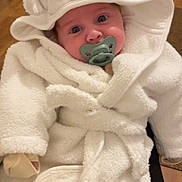 Caden joined the competition — help win amazing prizes! baby, infant, pacifier, white_bathrobe, hood, dog_face_hood, cute, cozy, indoor, floor, wooden_floor, plush, warm_clothing, child, portrait, person, sitting, hands_covered, soft_texture, adorable
