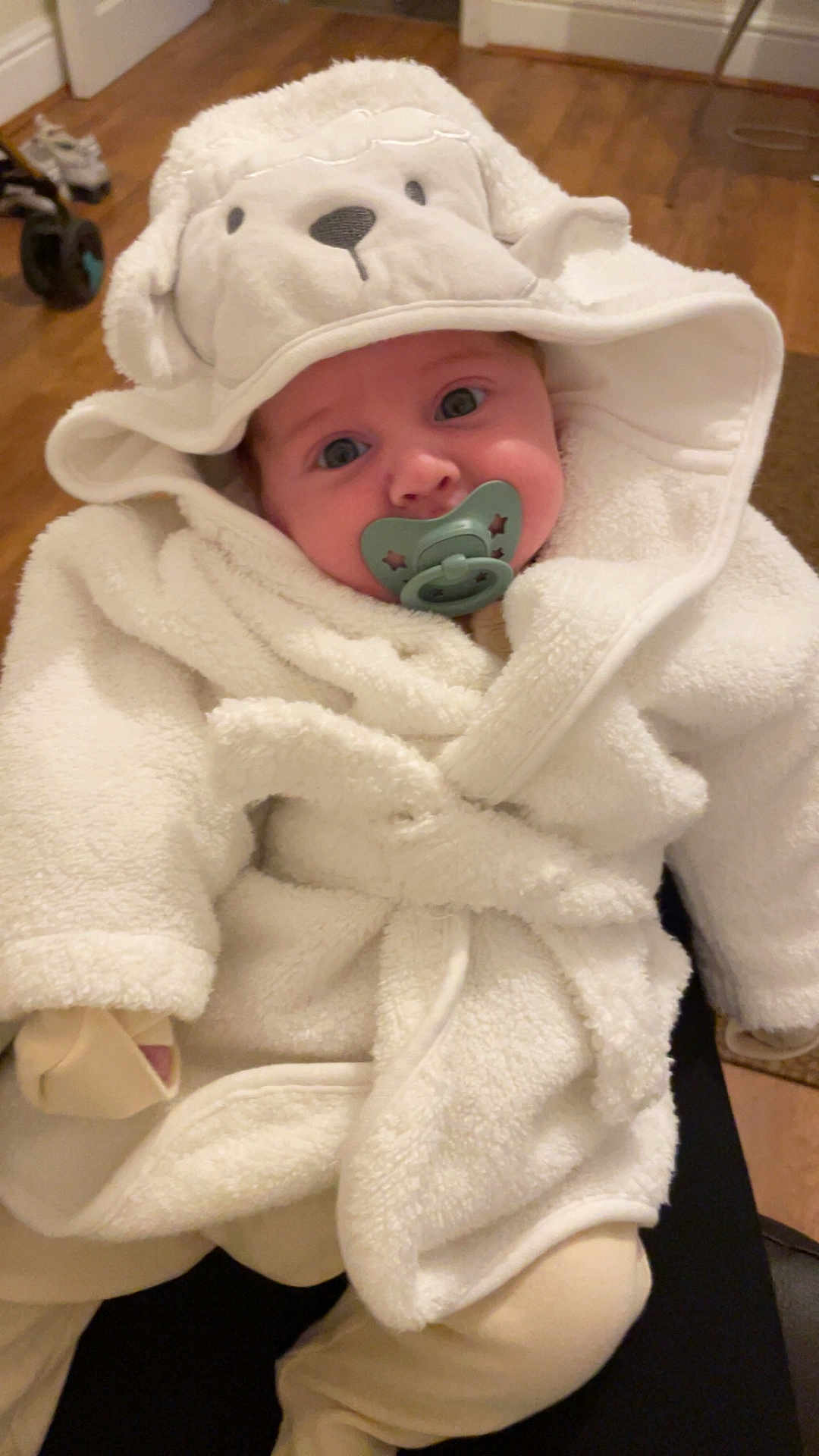 Caden joined the competition — help win amazing prizes! baby, infant, pacifier, white_bathrobe, hood, dog_face_hood, cute, cozy, indoor, floor, wooden_floor, plush, warm_clothing, child, portrait, person, sitting, hands_covered, soft_texture, adorable