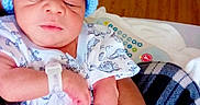 Emil joined the competition — help win amazing prizes! newborn, baby, infant, blue_hat, hospital, hospital_wristband, dinosaur_print, onesie, hand, adult_hand, cradling, bed, wooden_floor, blanket, portrait, indoor, person, sleepy, cute, child
