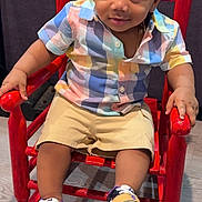Emil joined the competition — help win amazing prizes! toddler, child, rocking_chair, red_chair, colorful_shirt, shorts, sneakers, floor, indoor, smile, happy, cute, portrait, seated, wooden_chair, footwear, person, young_child, fashion, casual_clothing