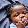 Emyla is registered to the contest to win money with this photo: baby, infant, pacifier, hand, curly_hair, close_up, face, skin, sleepwear, lying_down, soft_surface, expression, calm, cute, child, newborn, portrait, human, indoors, person