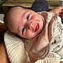 baby, smiling, face, blanket, bib, clothing, person, infant, hand, happy, closeup, indoor, table, wood, fabric, skin, cute, portrait, newborn, cozy