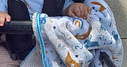 Gabriel is registered to the contest to win money with this photo: baby, child, stroller, blanket, tongue_out, happy, outdoor, concrete, footwear_free, clothing, hand, face, infant, smiling, cute, playful, baby_blanket, person, toddler, seat