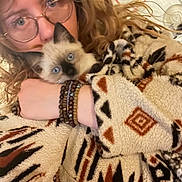 Yoko participe au concours pour gagner de l'argent avec cette photo : blanket, blue_eyes, bracelets, cat, close_up, cozy, curly_hair, cute, fabric_pattern, fur, glasses, hand, holding, indoor, kitten, person, pet, portrait, siamese_cat, sweater