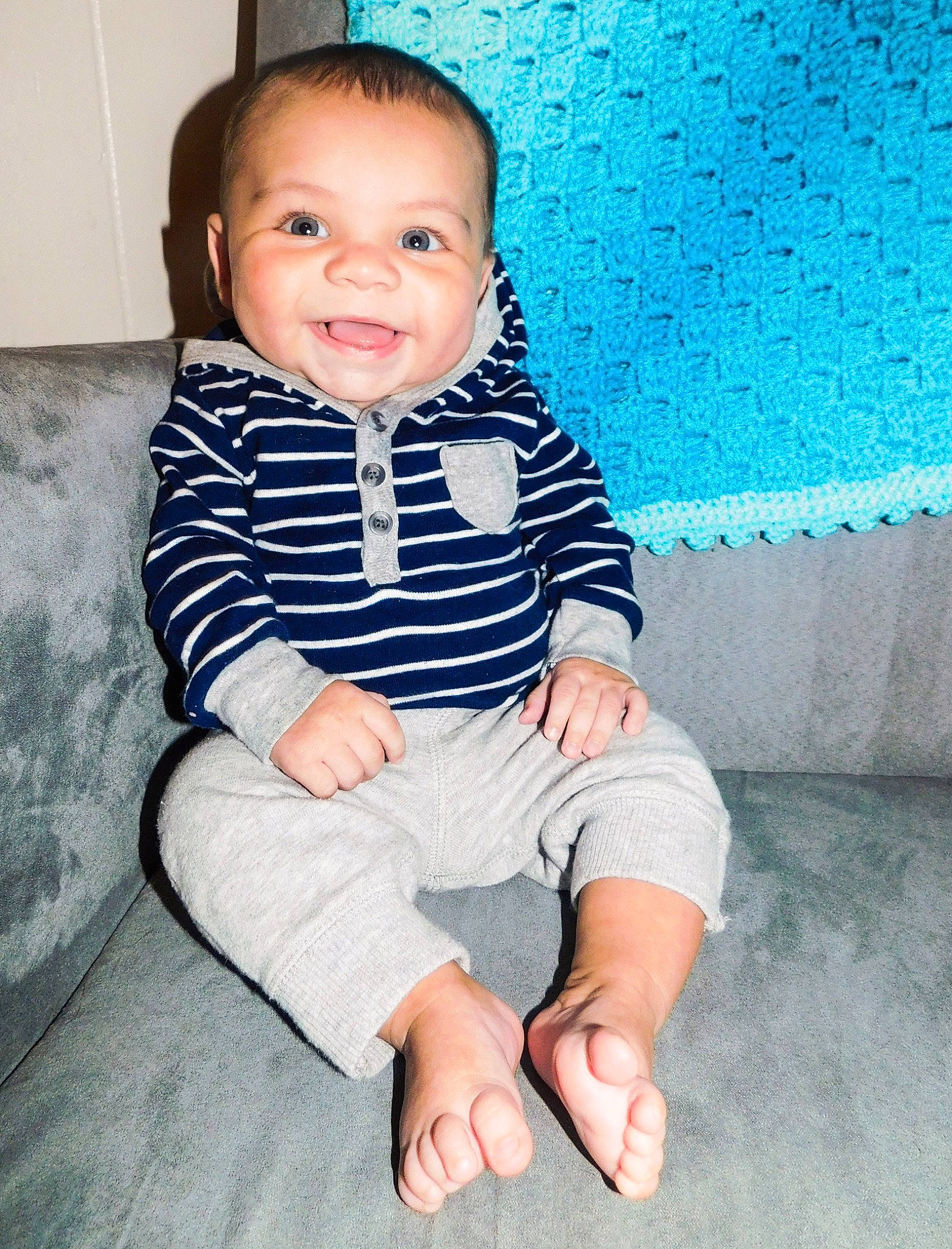 Aden is registered to the contest to win money with this photo: baby, baby_toddler_clothing, blue, cheek, child, face, facial_expression, floor, head, leg, person, sitting, skin, smile, standing, toddler, vacation