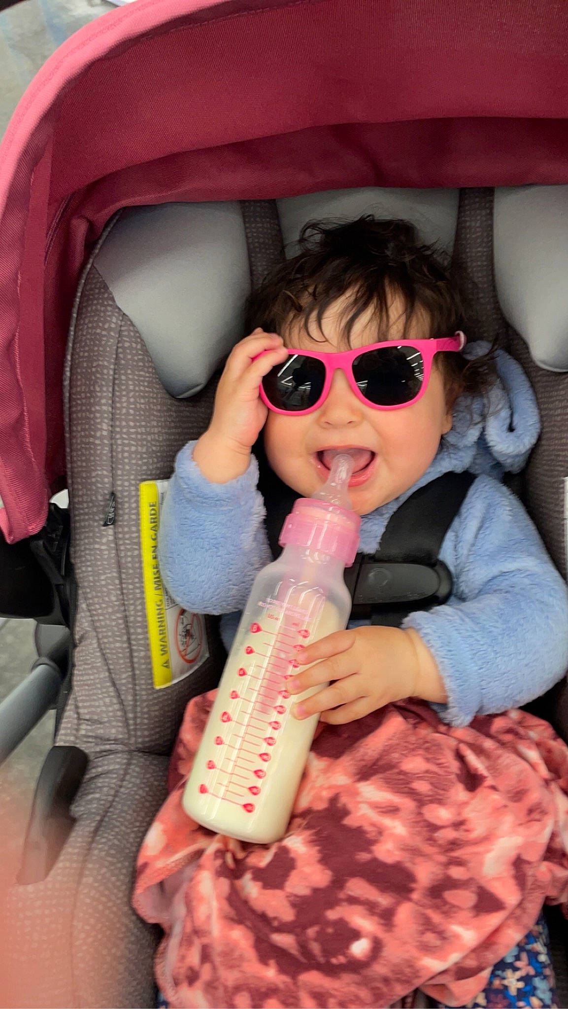 Macie is registered to the contest to win money with this photo: car_seat, cheek, comfort, eyelash, eyewear, face, finger, goggles, head, lip, mouth, nose, organ, person, pink, product, skin, sunglasses, toddler, toy