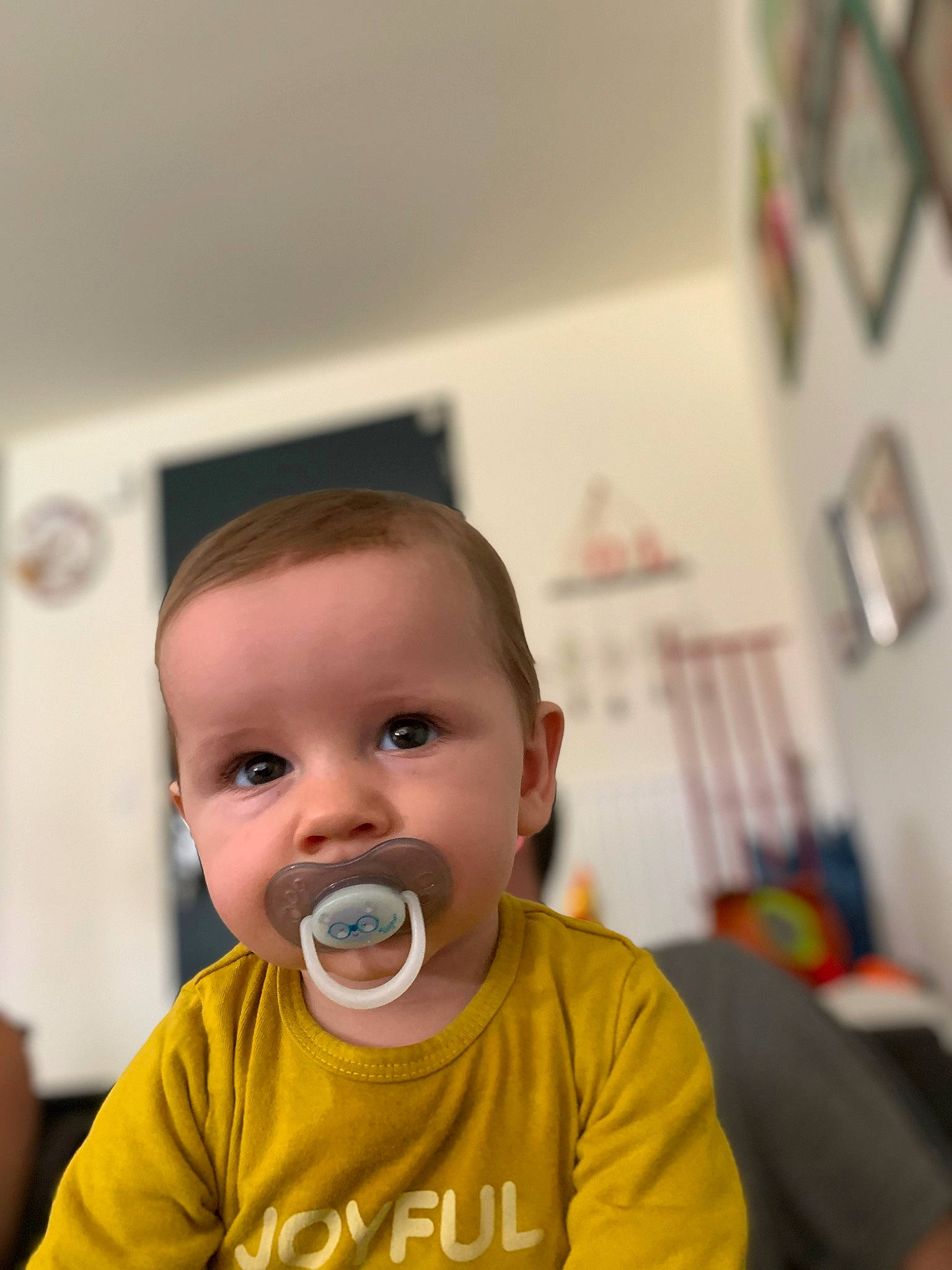 Logan participe au concours pour gagner de l'argent avec cette photo : baby, baby_toddler_clothing, cheek, child, clock, eyebrow, eyelash, facial_hair, happy, iris, moustache, neck, nose, person, picture_frame, room, sitting, sleeve, t_shirt, toddler