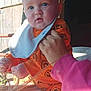 Michael is registered to the contest to win money with this photo: baby, child, orange_clothing, pumpkin_pattern, bib, hand, adult, animal, horse, barn, wooden_wall, outdoor, daylight, curious, blue_eyes, person, sitting, holding, pink_sleeve, closeup
