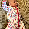 baby, sleeping, onesie, floral_pattern, cushion, texture, comfortable, peaceful, infant, closeup, relaxing, indoors, cute, soft, portrait, child, resting, cozy, pink, white