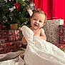 Kallen is registered to the contest to win money with this photo: baby, child, christmas_tree, holiday, presents, wrapping_paper, tissue_paper, red_curtain, smiling, happy, indoor, carpet, decorations, pine_cone, ribbon, festive, cute, portrait, celebration, young_child
