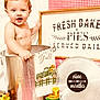 baby, child, metal_bucket, kitchen, decor, sign, towel, pie_tin, nine_months, gingham, red_background, vintage_truck, sunflowers, smiling, portrait, indoor, milestone, cute, playful, props