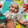 Orion is registered to the contest to win money with this photo: baby, smile, hat, toy, hand, playmat, colorful, dinosaur, infant, child, cute, happy, lying_down, fabric, pattern, person, playtime, indoors, soft_toy, closeup