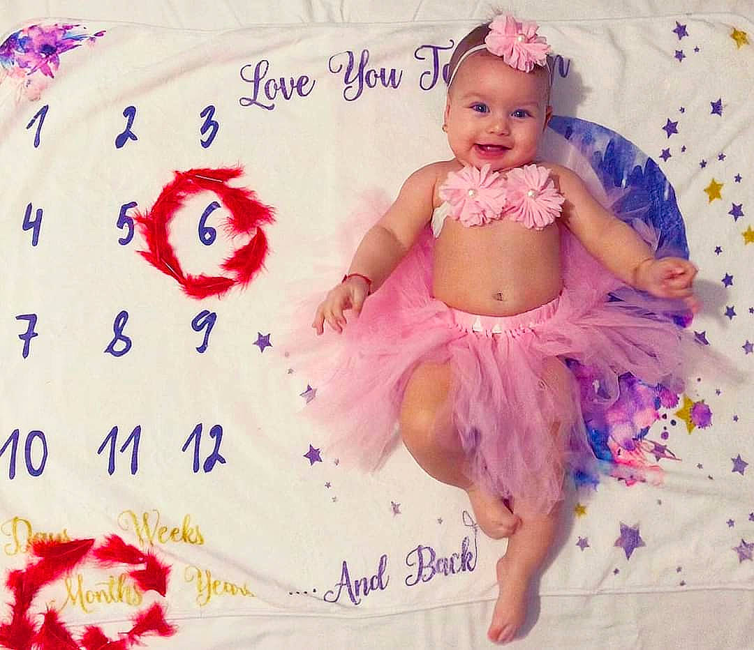 Soraya a rejoint le concours — aidez-le/la à gagner de superbes lots ! abdomen, baby, baby_products, baby_toddler_clothing, child, costume_hat, event, font, happy, headband, headpiece, headwear, joy, linens, magenta, pattern, person, petal, pink, sitting