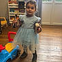 Nola a rejoint le concours — aidez-le/la à gagner de superbes lots ! blue_dress, books, bookshelf, child, curtains, cute, flooring, furniture, girl, indoor, makeup_brushes, natural_light, person, playroom, rain_boots, smiling, toy_car, tutu_dress, window, wooden_floor