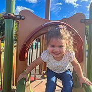 Nola a rejoint le concours — aidez-le/la à gagner de superbes lots ! blue_jeans, blue_sky, casual_clothing, child, clouds, daylight, fun, girl, green_slide, hair_clip, happy, metal_rails, outdoor, park, play_equipment, playground, recreation, short_sleeve_shirt, slide, smile