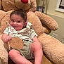 Emin is registered to the contest to win money with this photo: baby, teddy_bear, plush_toy, indoor, smiling, child, milestone, wooden_plaque, cute, sitting, happy, shirt, shorts, feet, couch, face, person, home, celebration, infant