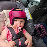 Novalee is registered to the contest to win money with this photo: baby, child, car_seat, helmet, pacifier, blue_eyes, blanket, car_interior, seatbelt, safety, infant, pink_helmet, clothing, person, toddler, window, car_door, headgear, cute, sitting