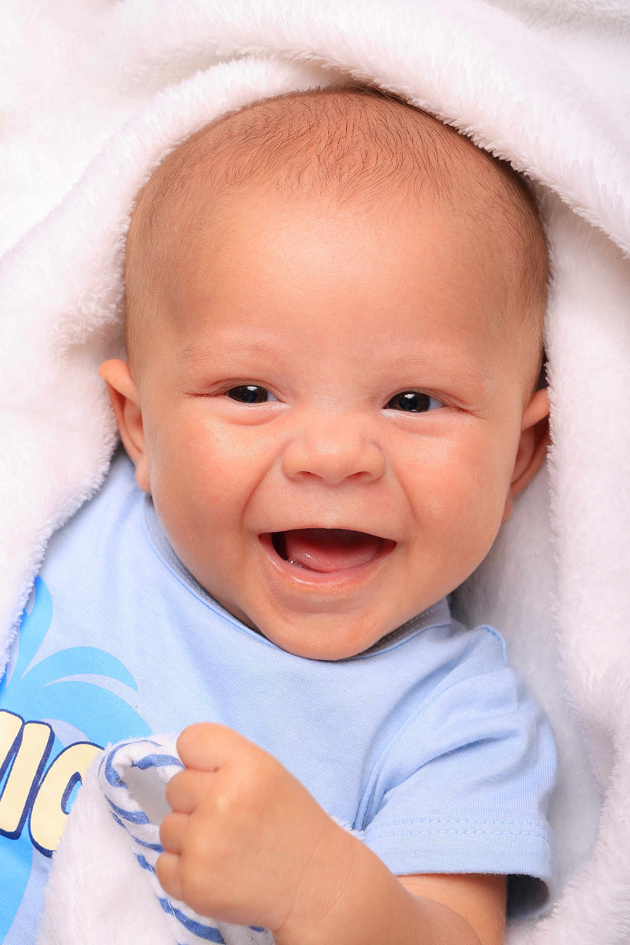 Maël a rejoint le concours — aidez-le/la à gagner de superbes lots ! baby, infant, smile, happy, face, blue_shirt, blanket, flesh_tone, cute, child, newborn, young, human, portrait, closeup, skin, expression, joy, hand, warm