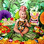 Blakely is registered to the contest to win money with this photo: baby, child, smiling, headwrap, floral_outfit, tropical, lei, colorful, decorations, greenery, paper_fans, smile, sitting, portrait, cute, indoors, celebration, festive, happy, aloha_sign
