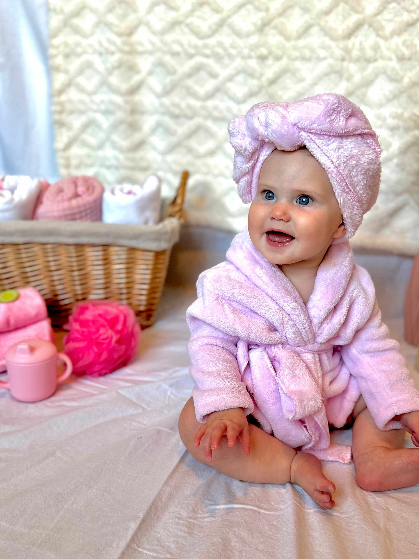 Blakely is registered to the contest to win money with this photo: baby, child, pink, bathrobe, towel, smile, blue_eyes, sitting, blanket, basket, rolled_towels, bath_accessories, soft, cute, indoors, skin, hand, foot, happy, portrait