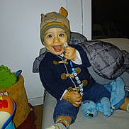 Lowenn participe au concours pour gagner de l'argent avec cette photo : beaded_chain, beanie, blanket, blue_toy, child, clothing, couch, face, hand, happy, indoor, pacifier, person, plush_toy, smile, sock, sweater, toddler, toy, warm_clothing