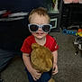 Ashton is registered to the contest to win money with this photo: barefoot, blue_pants, carpet, child, cute, dog, furniture, happy, home, indoor, person, playful, red_shirt, shelf, smiling, sunglasses, teddy_bear, toddler, toy, young_child