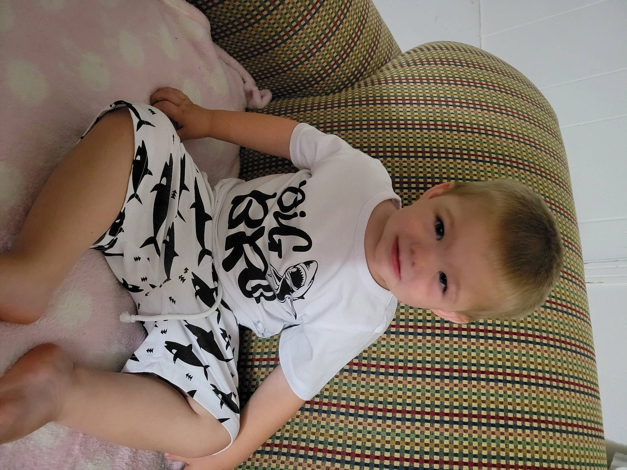 Dezmond is registered to the contest to win money with this photo: baby, baby_products, baby_sleeping, baby_toddler_clothing, comfort, elbow, eye, finger, hairstyle, head, human_body, human_leg, joint, leg, pattern, person, sitting, skin, sleeve, thigh