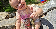 Ma'Kayla is registered to the contest to win money with this photo: child, girl, smiling, outdoors, rocks, forest, nature, fish, fishing, wildlife, summer, sunlight, portrait, crouching, blonde_hair, t_shirt, shorts, shoes, cooler, adventure