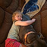 child, toddler, sleeping, dog, pet, couch, sofa, blanket, nap, portrait, indoor, home, cozy, resting, companion, brown_dog, pink_shorts, gray_shirt, relaxed, photography