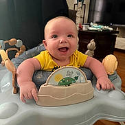 Oliver joined the competition — help win amazing prizes! baby, smiling, indoor, yellow_shirt, activity_center, toys, happy, infant, furniture, television, wooden_floor, face, person, child, home, cute, plush_toy, seat, expression, bright